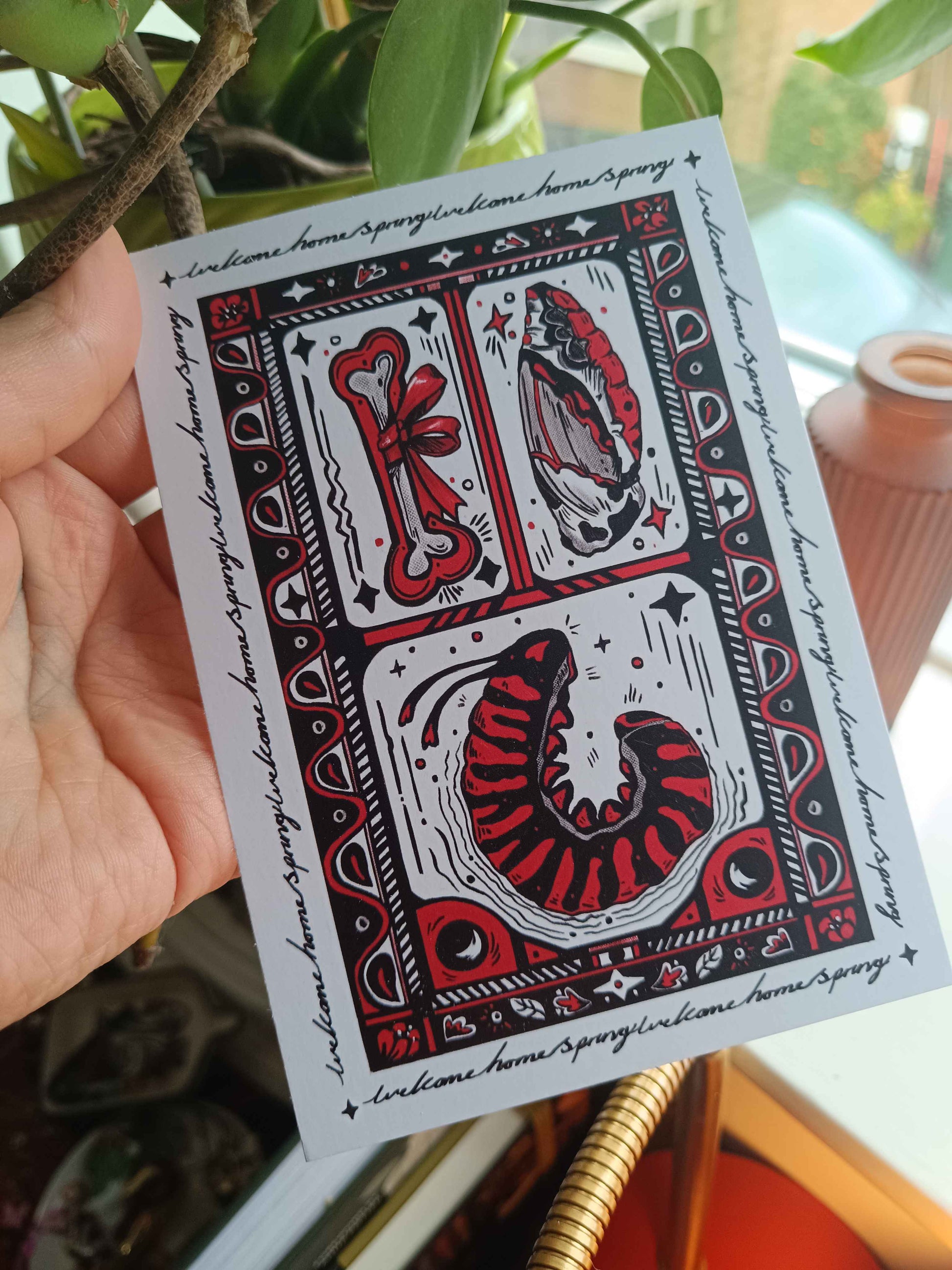 A postcard sized print with a caterpillar and other whimsy objects and trinkets